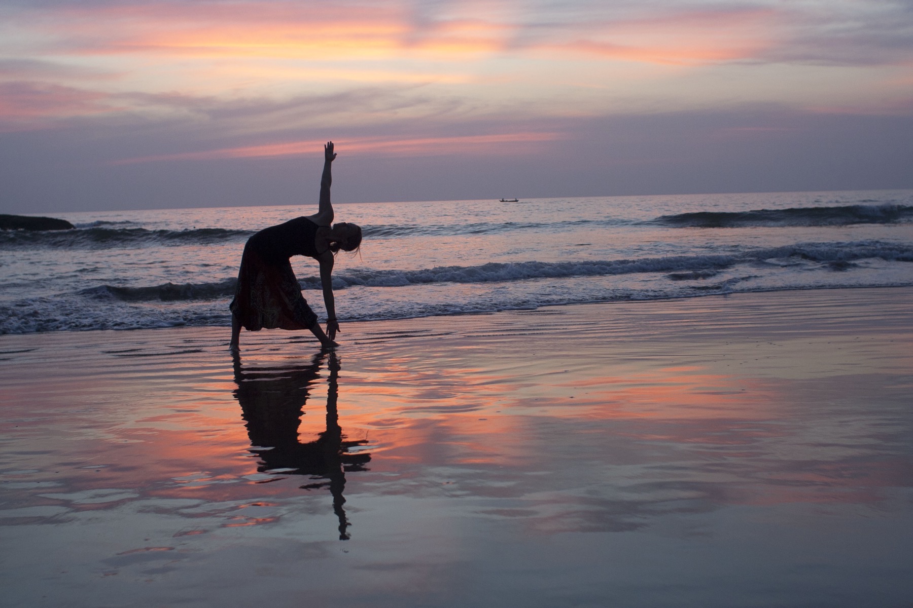 A yoga silhouette on the sand at sundown, the sea calm.